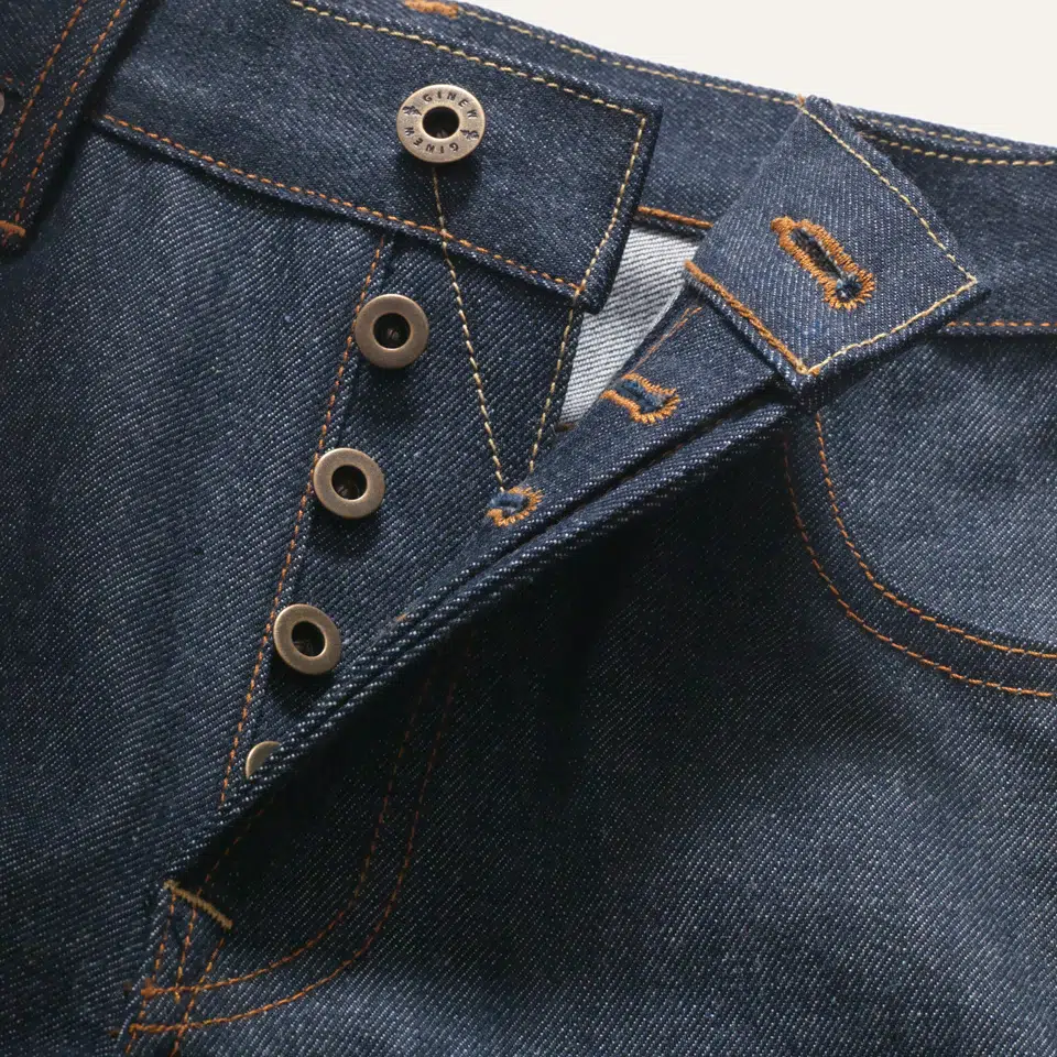 A closeup of a button fly on American-made dark wash jeans.