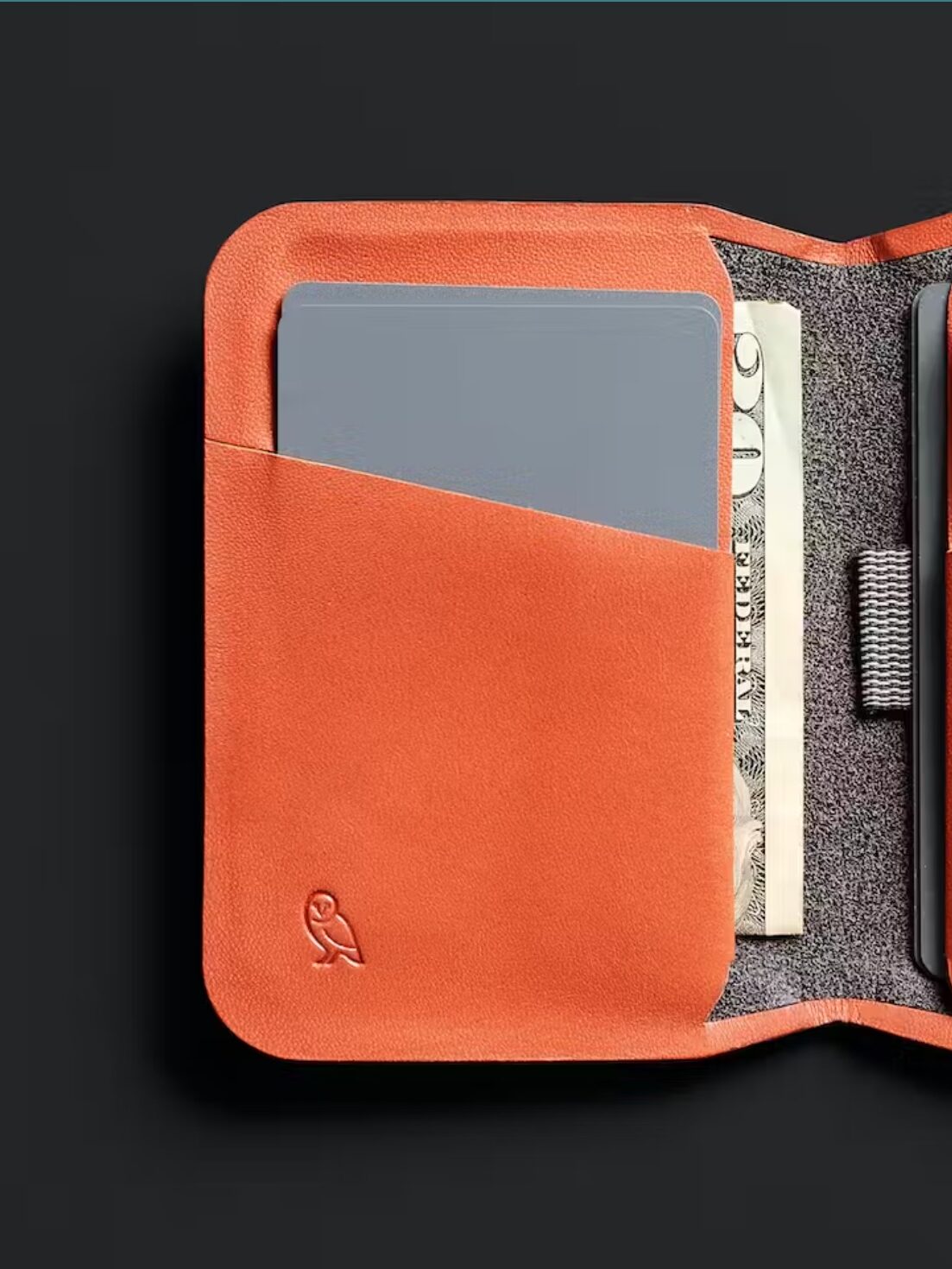 Half of an open orange wallet with cards and money visible.