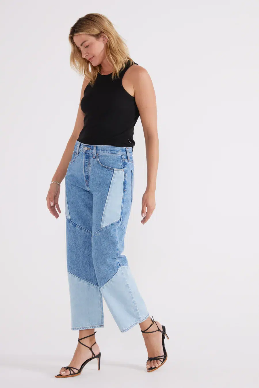 model wearing wide leg cropped denim with various patches of light and dark denim
