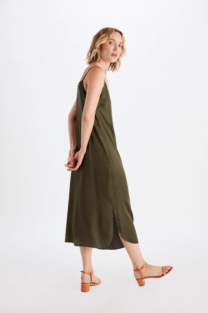 A model looks over her shoulder in an olive slip dress.