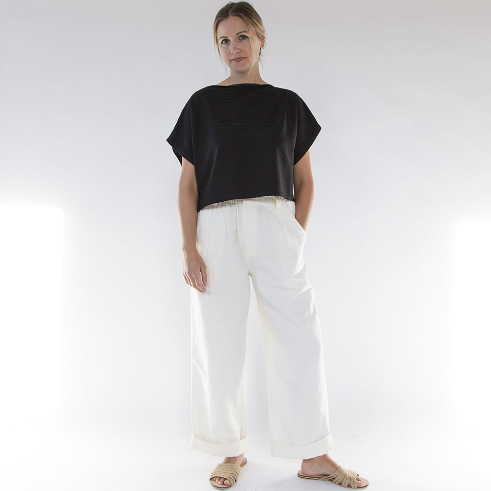 A model in white pants and a black shirt.
