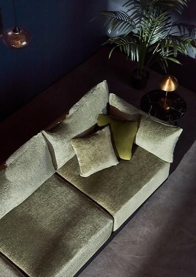 A green boucle couch shot in a styled interior from above.