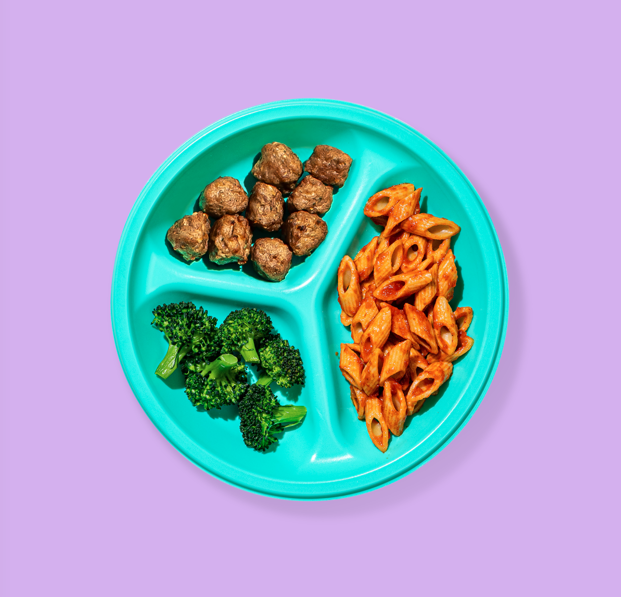 A teal toddler sectioned plate with broccoli, cut penne with tomato sauce, and small meatballs. 