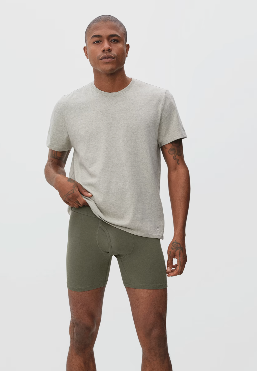 A model in a gray tee and olive green boxer briefs.