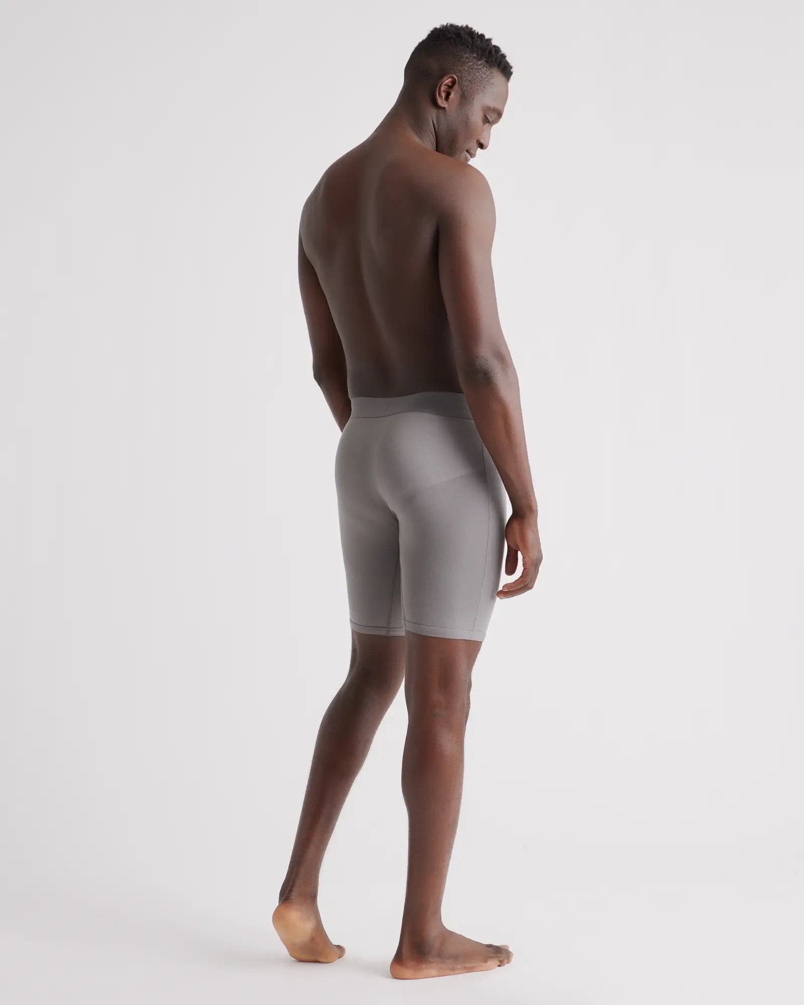 A model faces away, wearing gray 8" long boxer briefs.