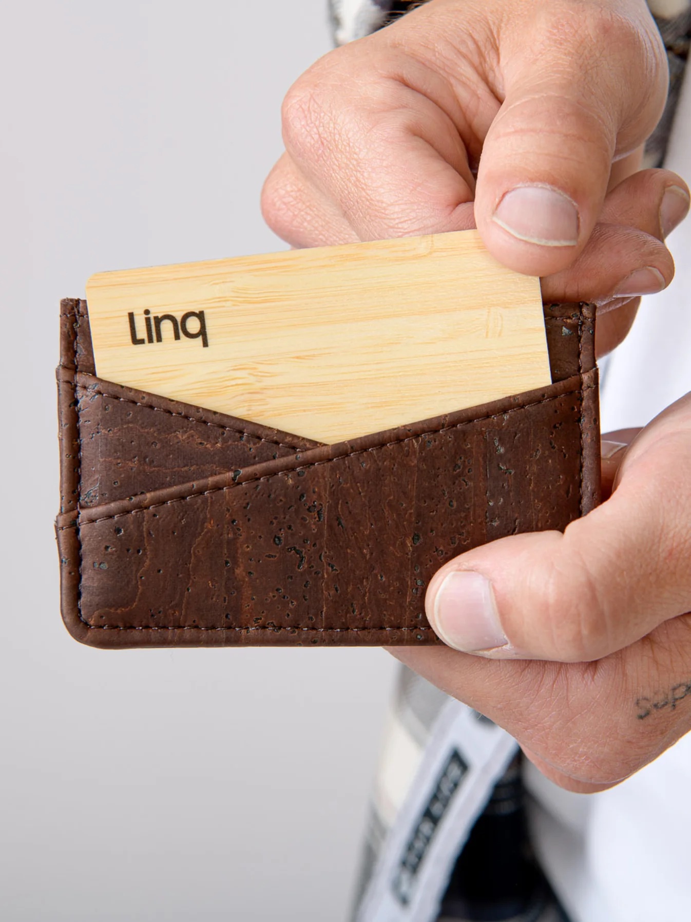 Close up of hands pulling a card from a cork wallet. 