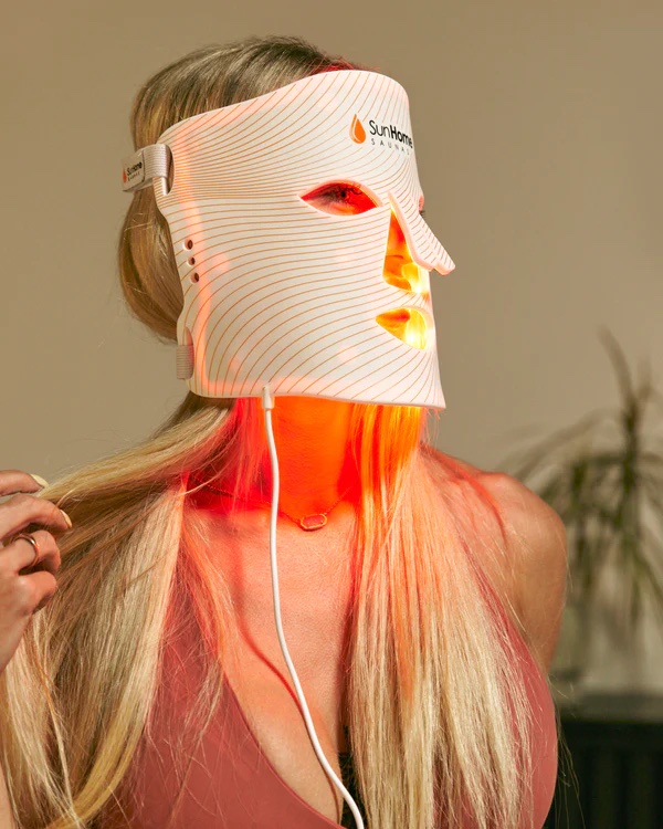 A moderl wears a red light mask. 