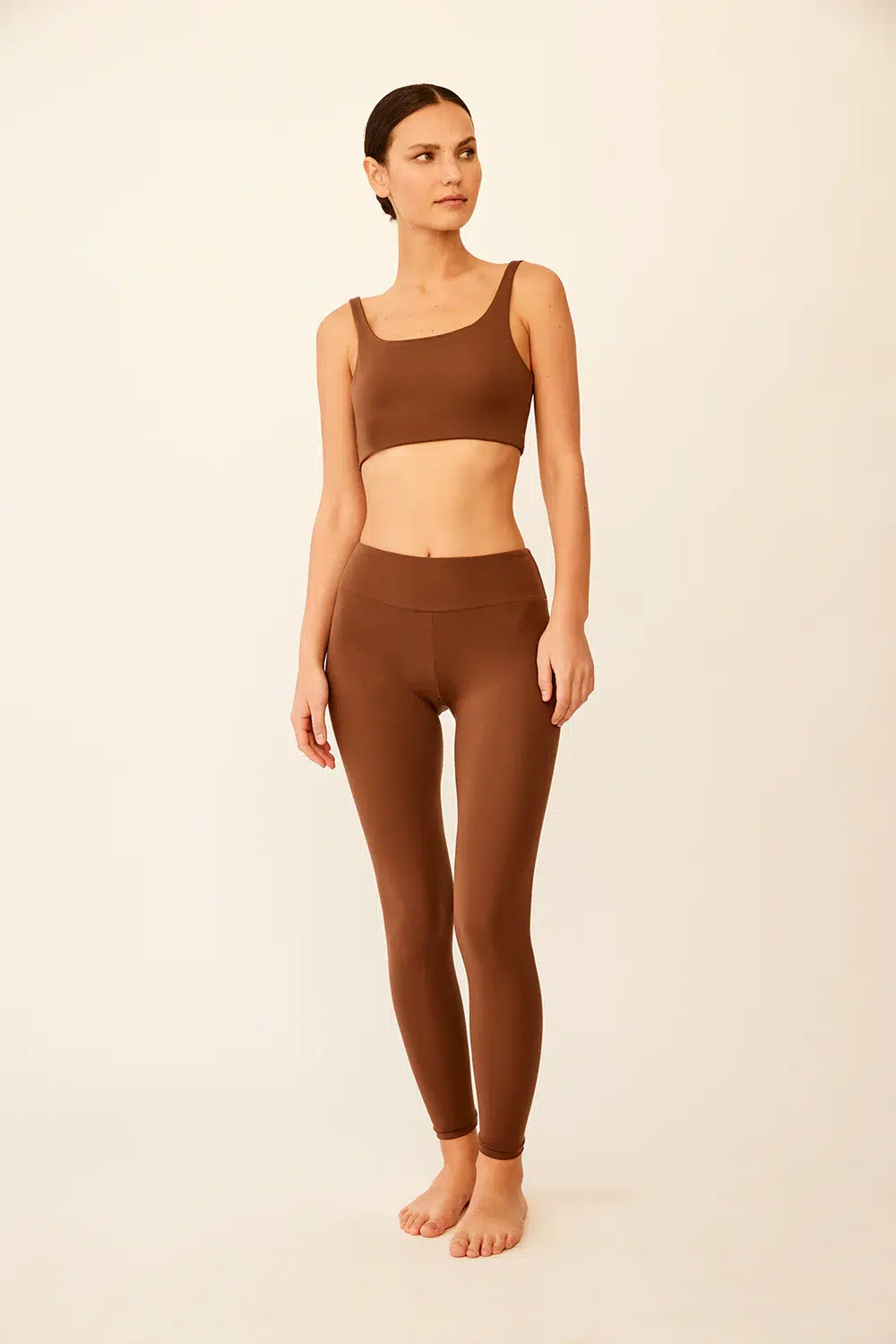 A model wears a brown sports bra and leggings set. 