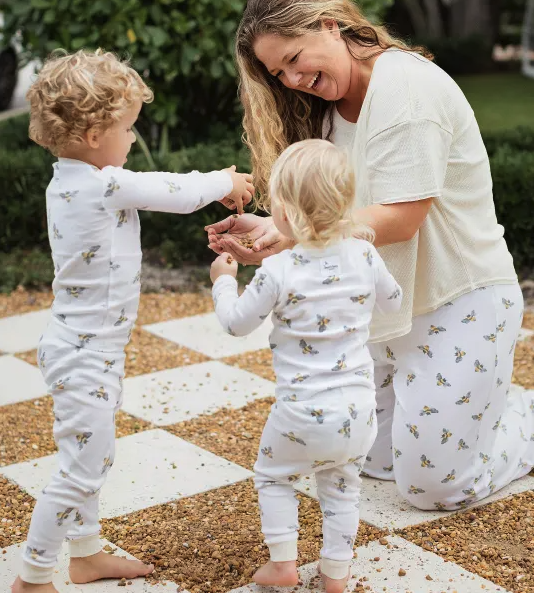 A parent smiling at two children while all wearing matching Burt's Bees pajama sets.