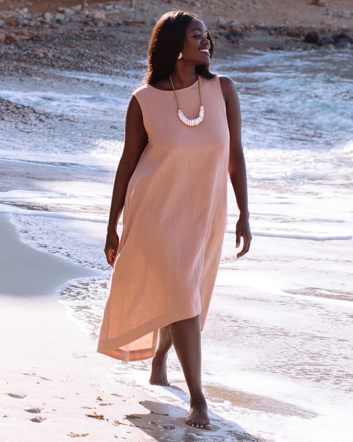 A model on the beach wearing a dusty pink linen shift.