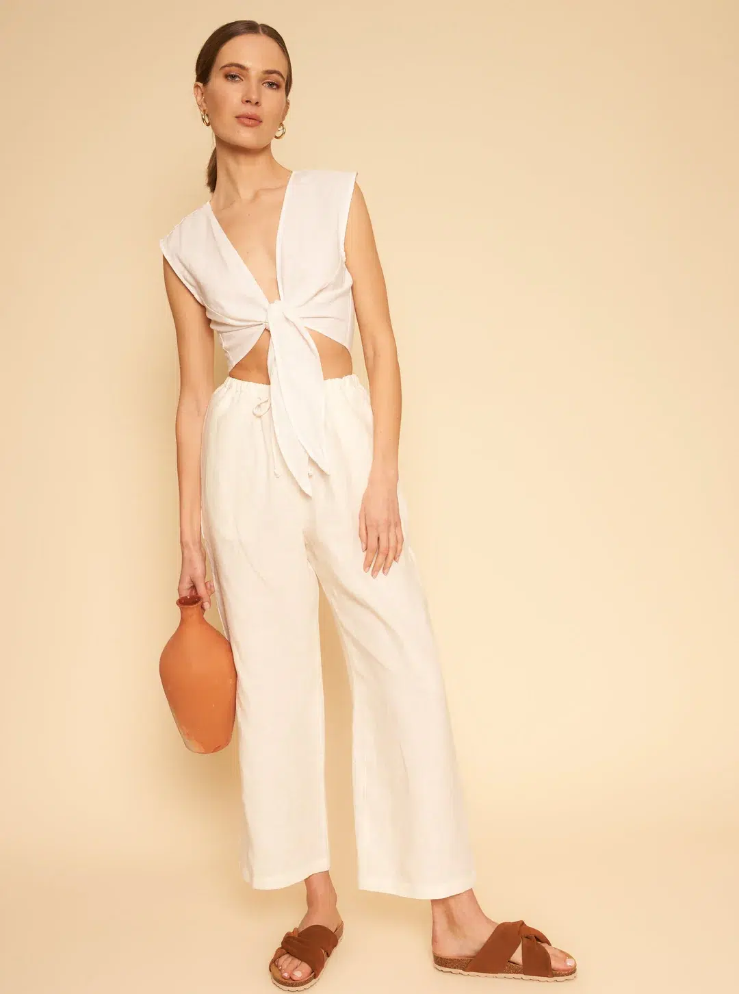 A model wearing a cream wrap top with matching wide leg pants. 