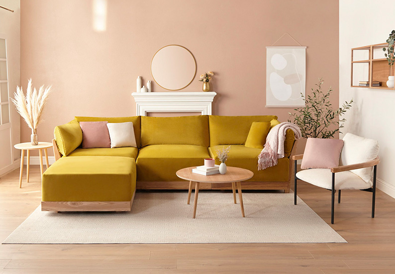 A goldenrod-colored sectional sofa in a styled pink interior.