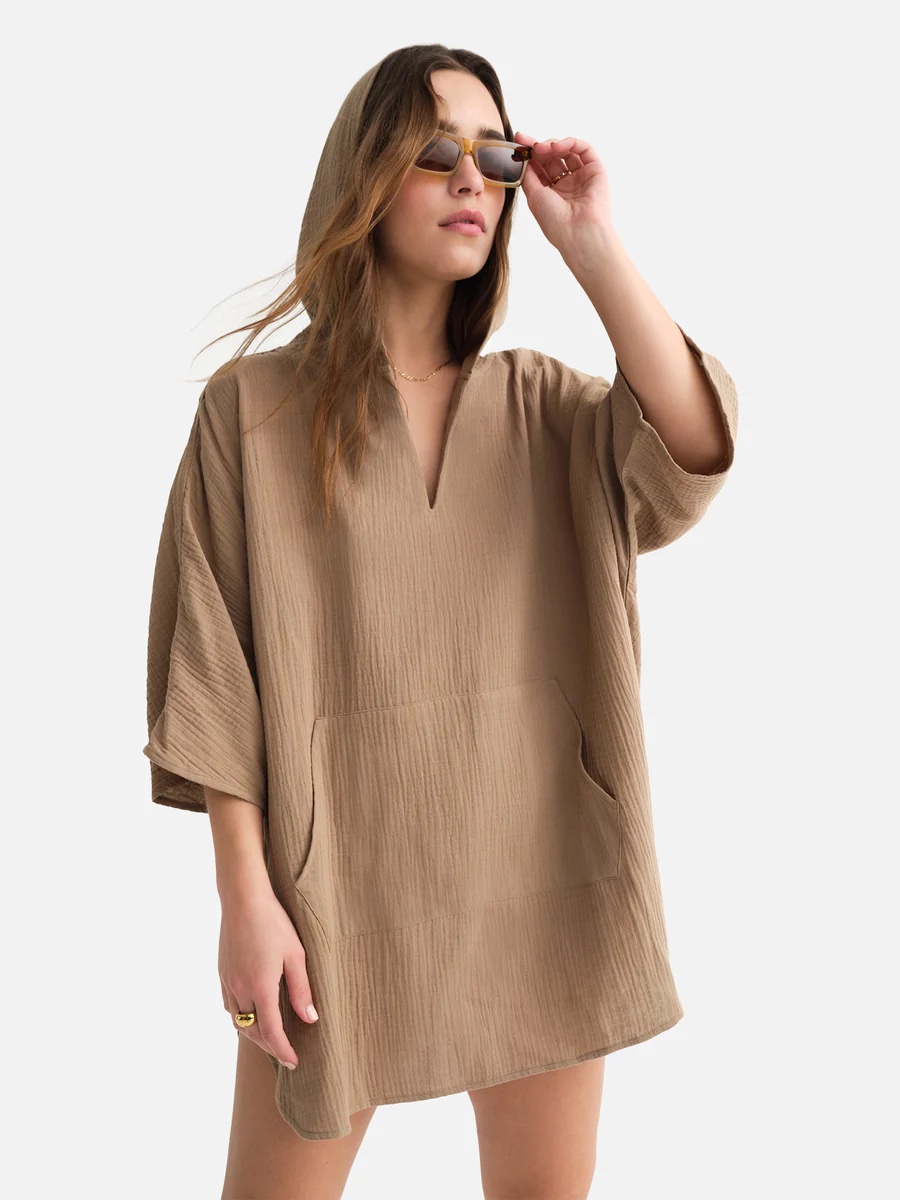 A model in a tan coverup and sunglasses.