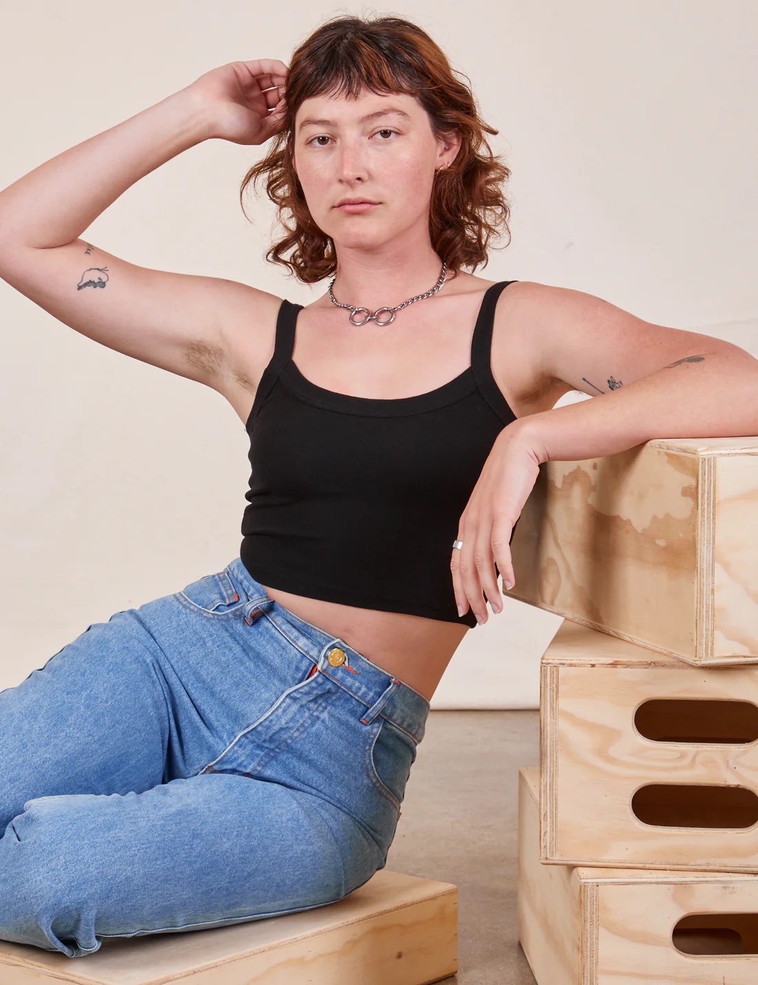 A model in jeans and a black cropped tank.
