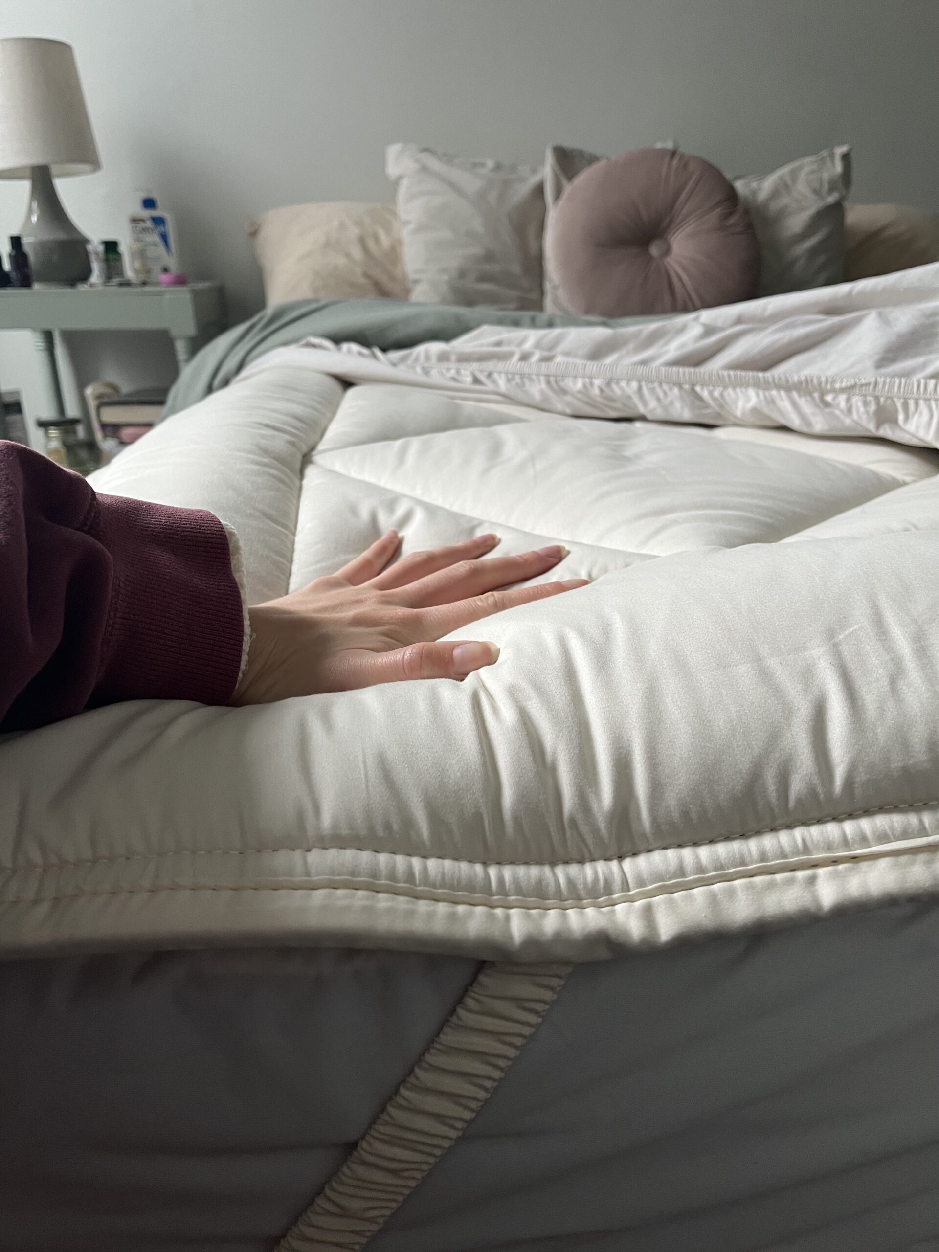 A hand presses into the mattress topper. 