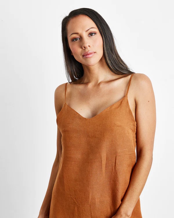A model wears a rust-colored linen slip dress.