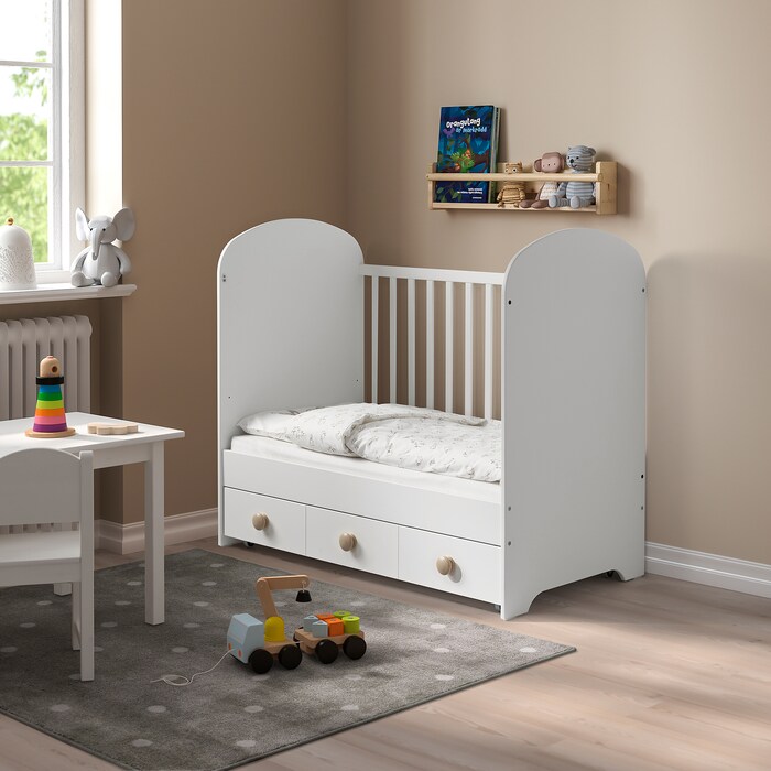 A white toddler bed with drawers.