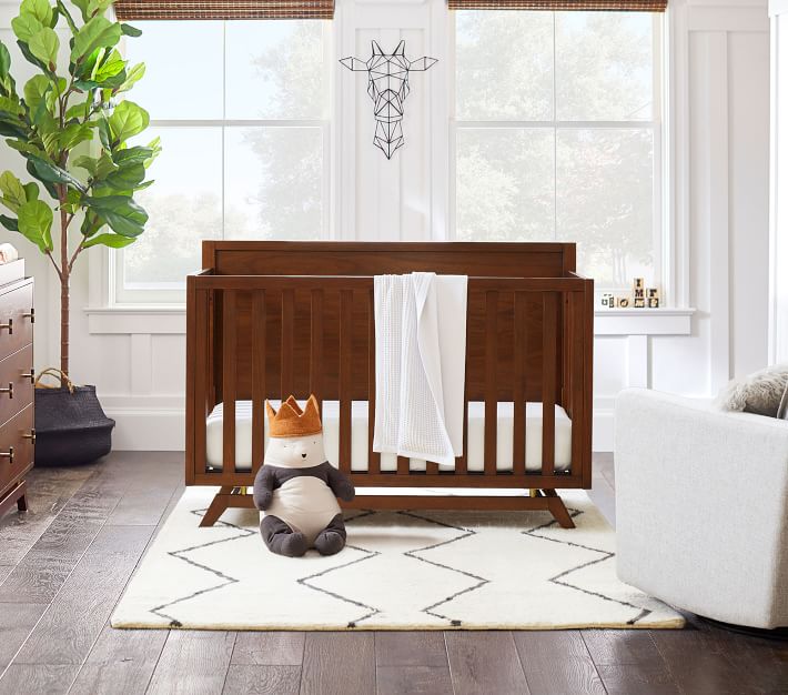A dark brown wooden crib in a nursery.