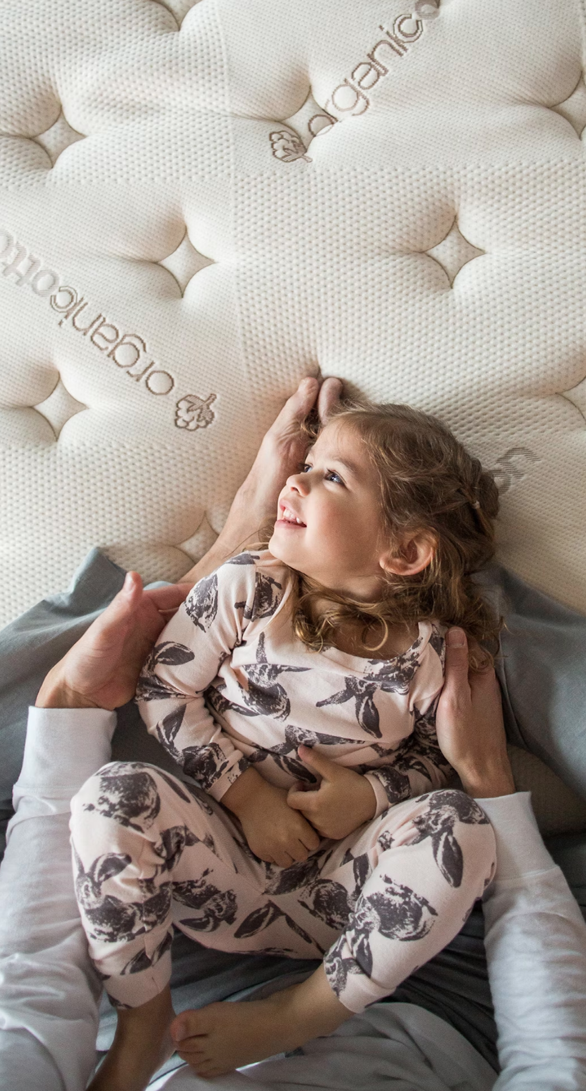 A child lies in the lap of an adult on an eco-friendly foam mattress. 