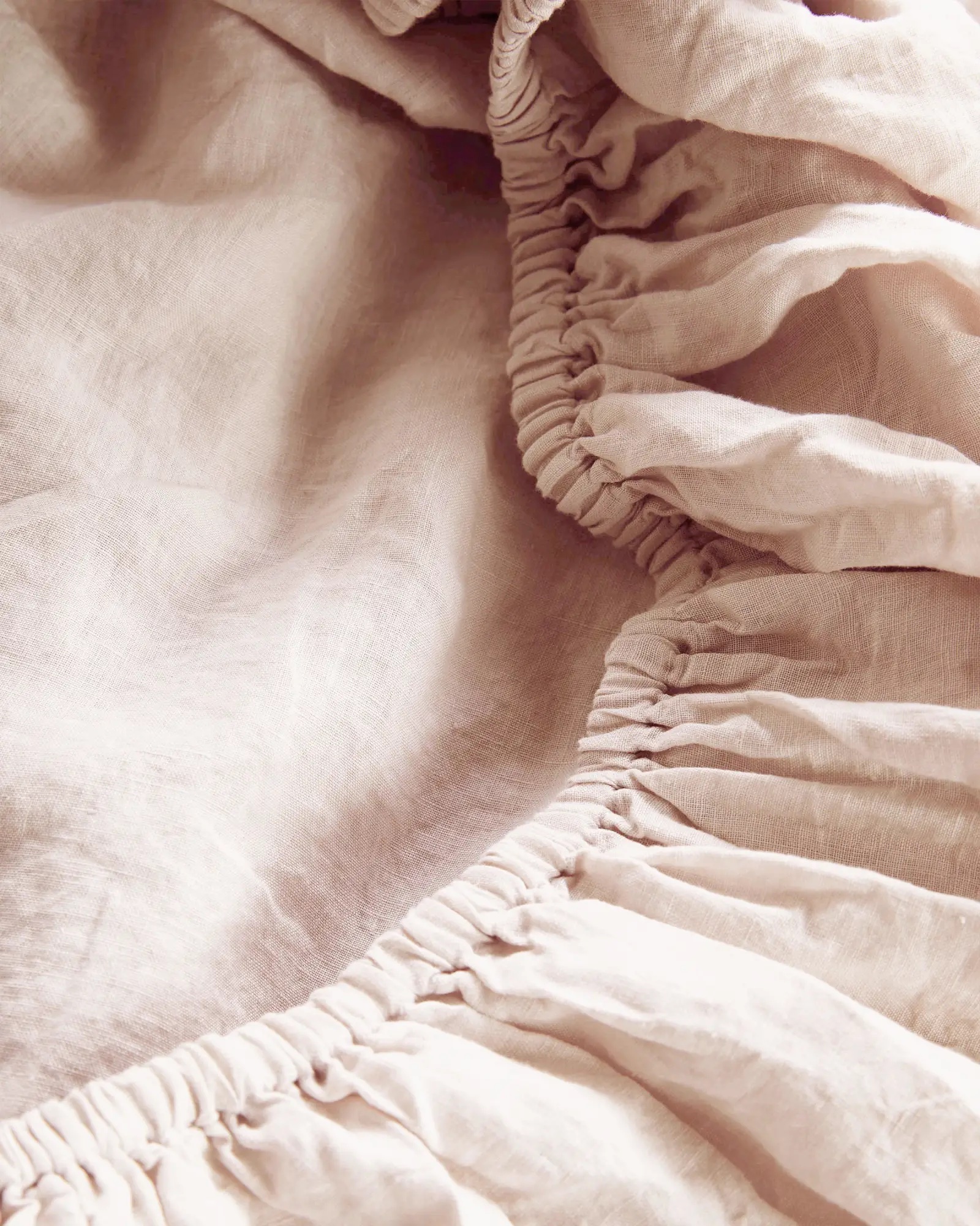 A detailed shot of a pink fitted linen sheet.