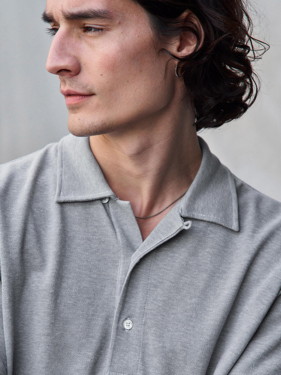A close up of a model wearing a gray polo.