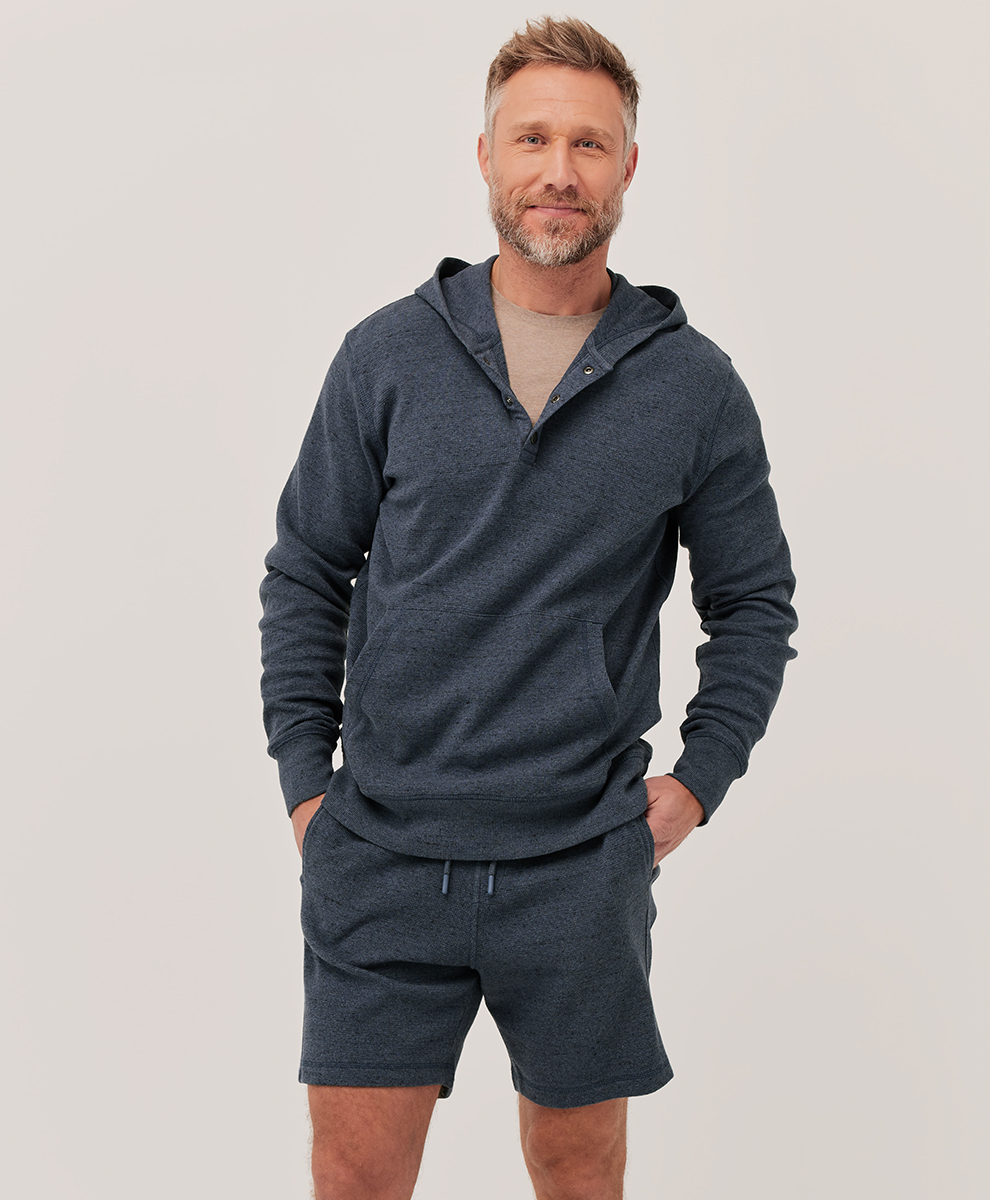 A man wearing a slate blue hoodie and matching soft shorts.