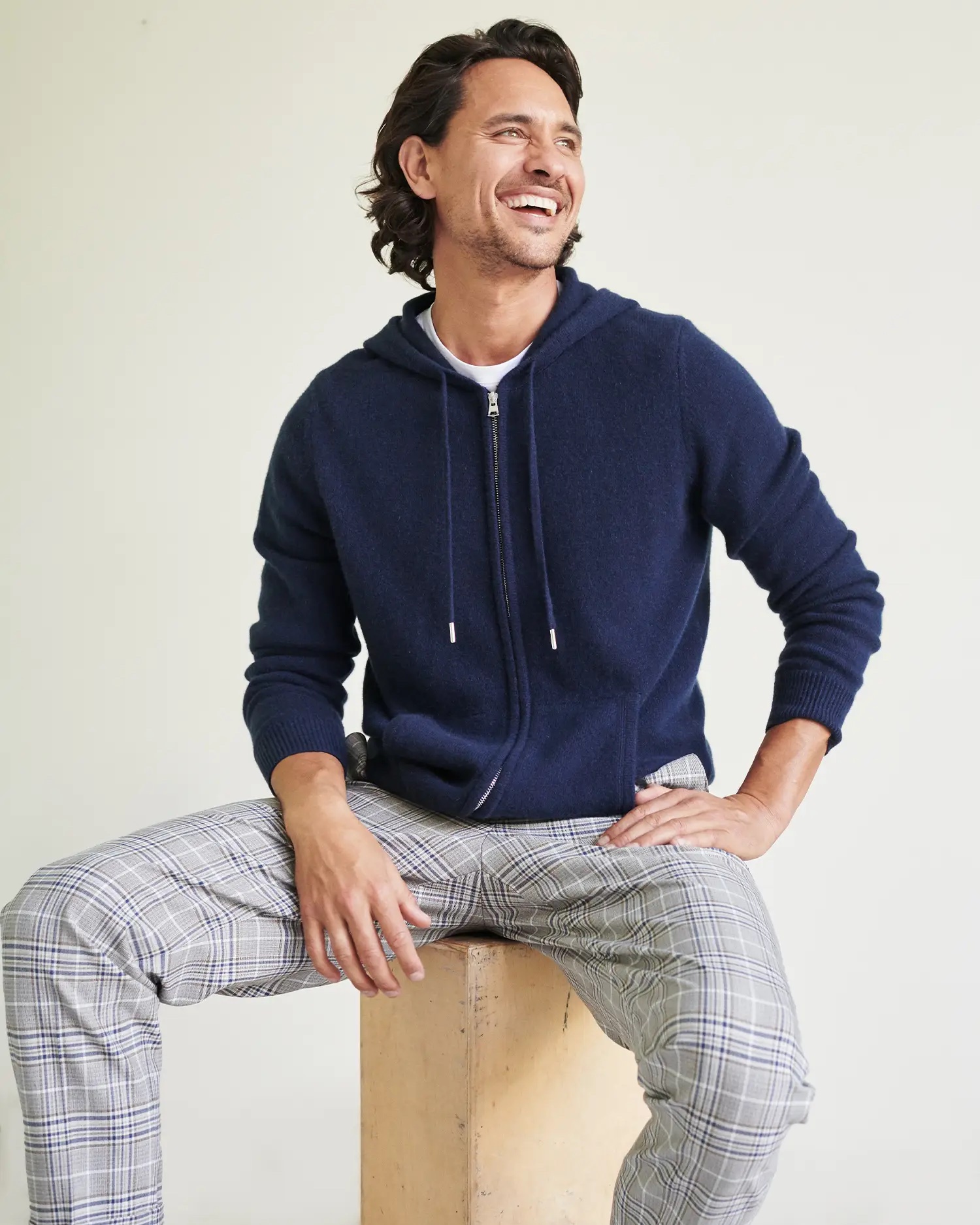 A model in a navy cashmere zip up hoodie and plaid pants.