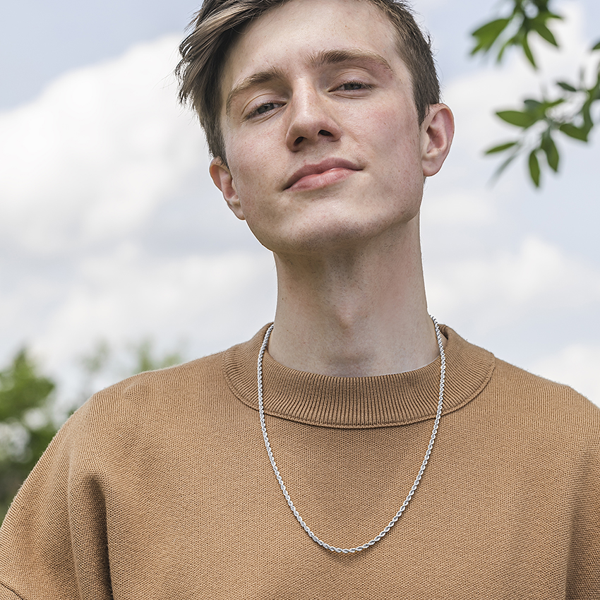 A model wears a chain over his sweatshirt. 