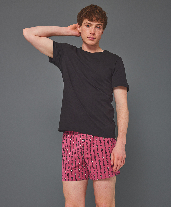 A model in a black tee and pink patterned boxers.