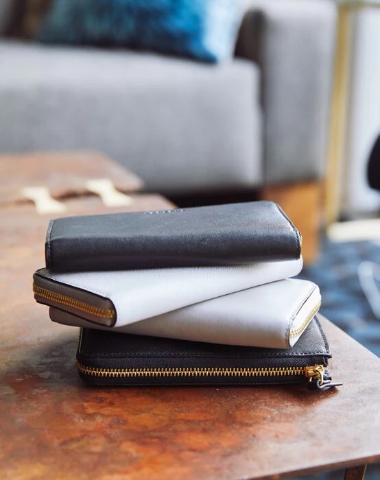 A stack of leather zip close wallets on a table.