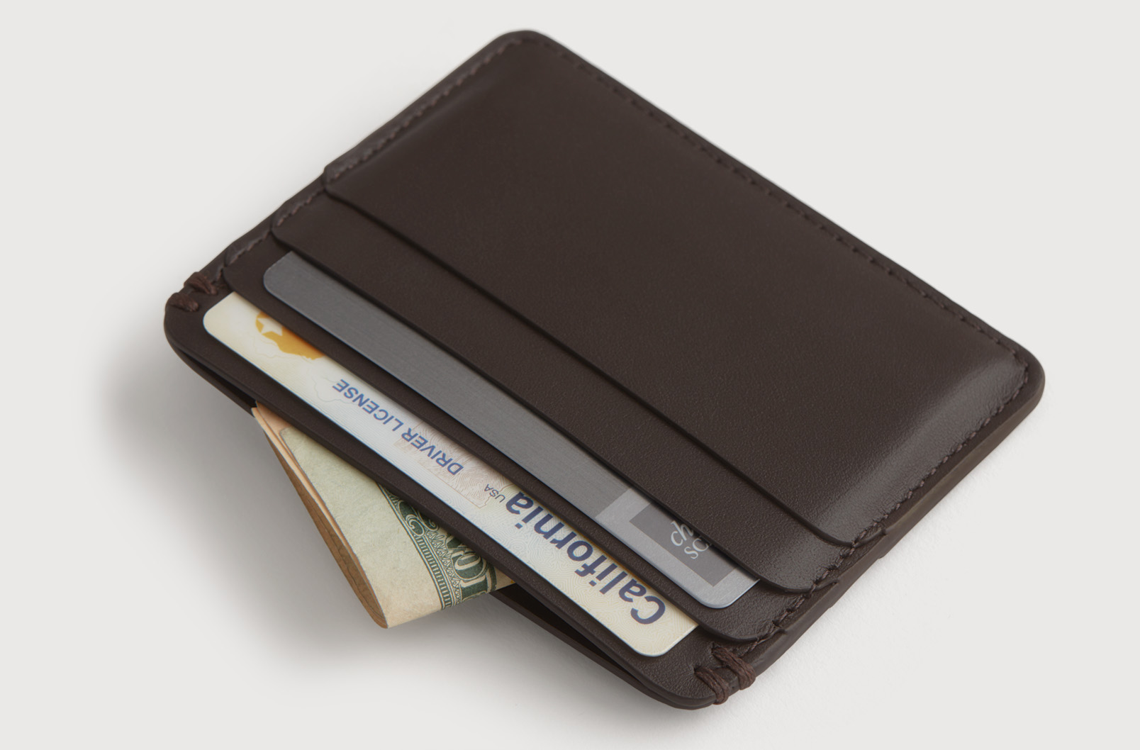A leather cardholder with cash and cards in it.
