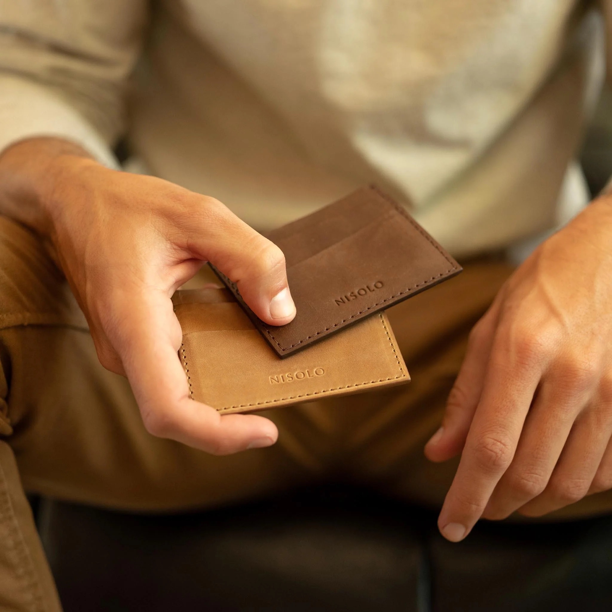 Close up of a man's hands holding two empty leather card cases.
