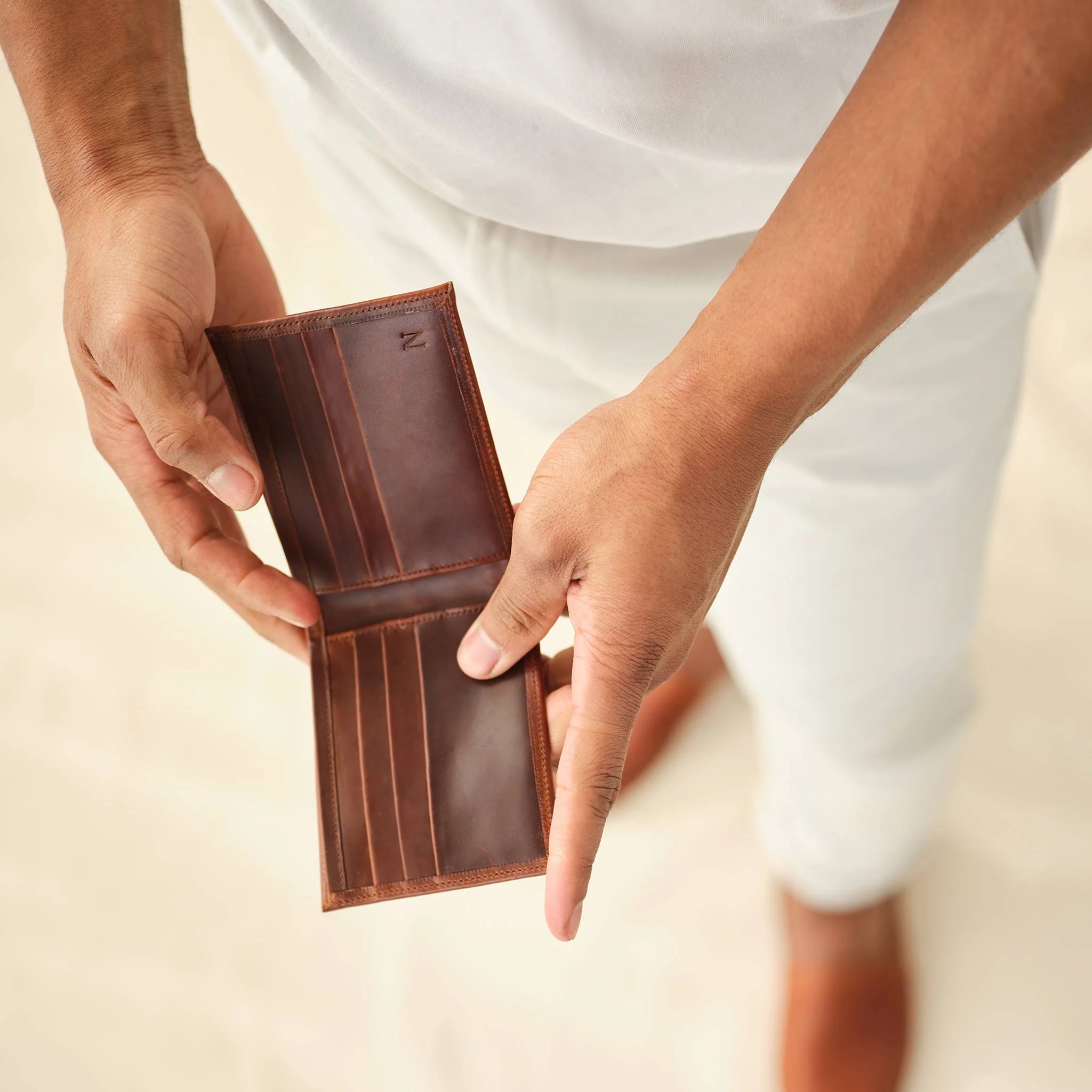 Close up of a man's hands opening an empty leather wallet. 