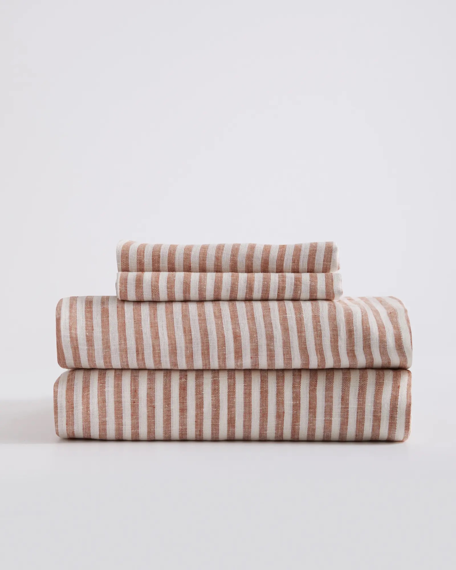 White and red striped linen sheets folded in a stack.