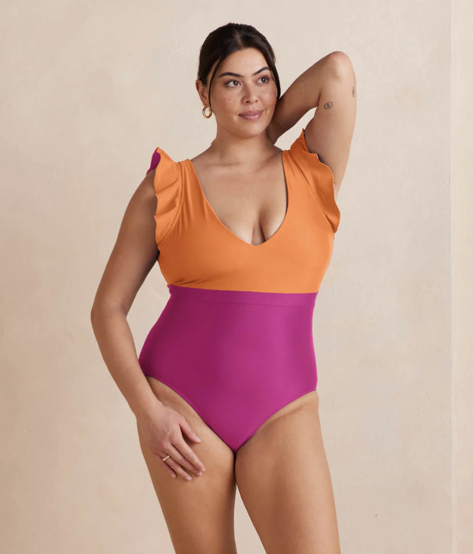A model in a colorblocked one piece with ruffled sleeves.