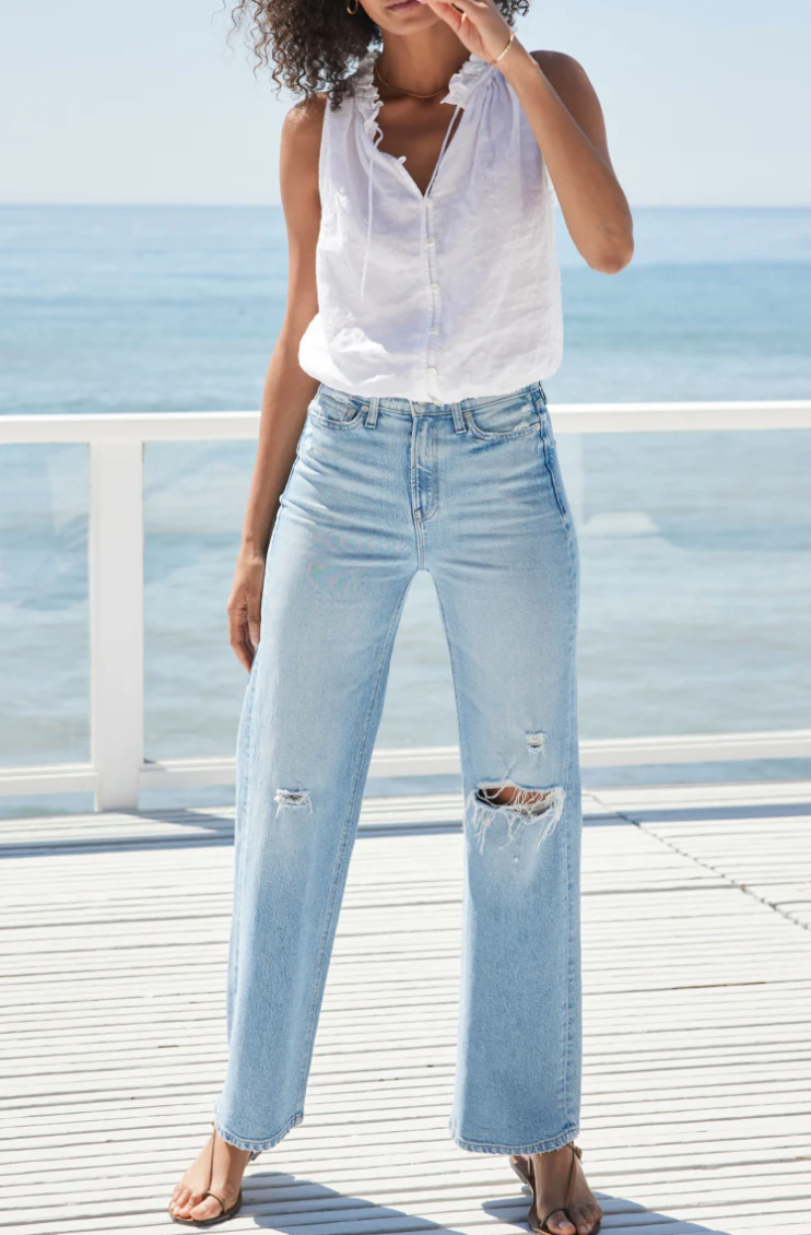 A model in American-made light wash wide leg jeans with ripped knees.