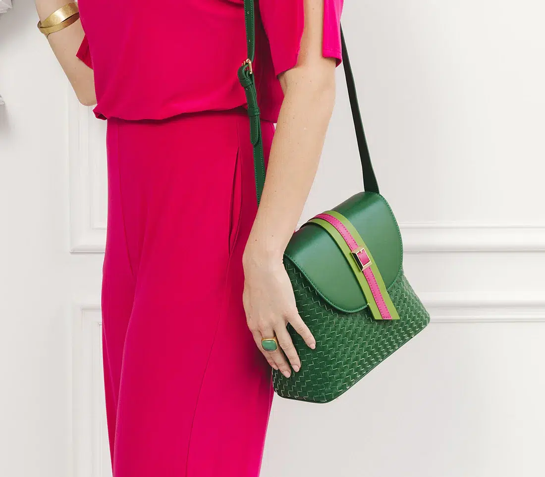 A green and pink handbag on a model's body with only the hot pink shirt and pant visible. 
