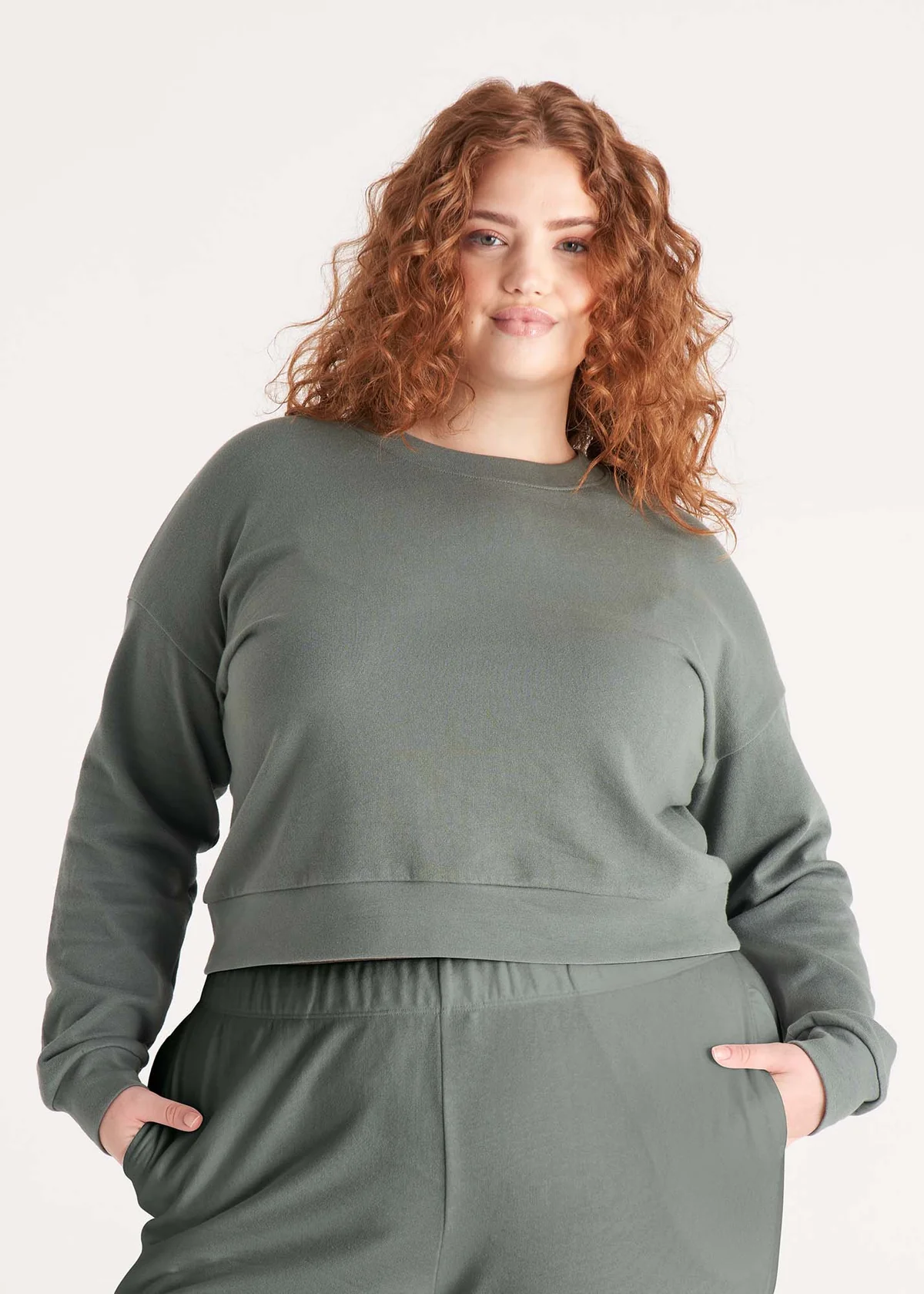 A plus size model in a sage green sweat set. 