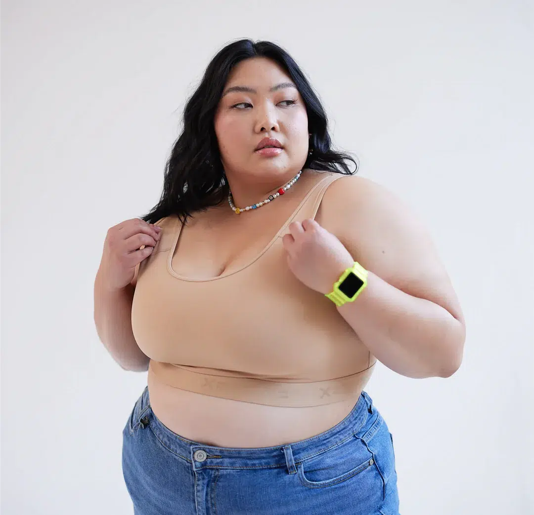 A plus size model in a sports bra and jeans. 