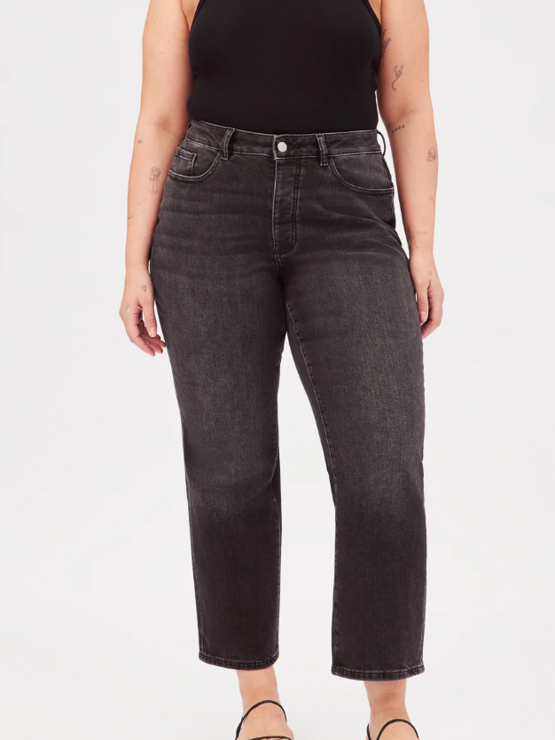 A plus size model in black straight leg jeans. 