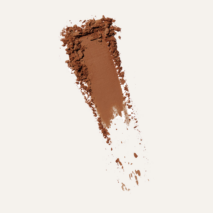 A sample of Well People powder foundation in a darker shade on an off-white backgound. 