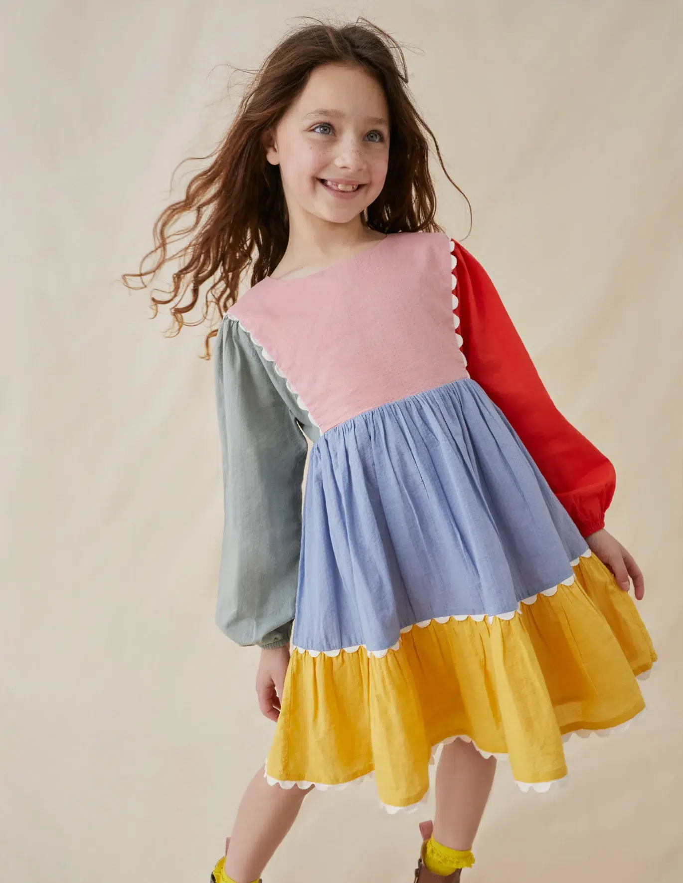 A girl in a colorblocked dress smiles. 