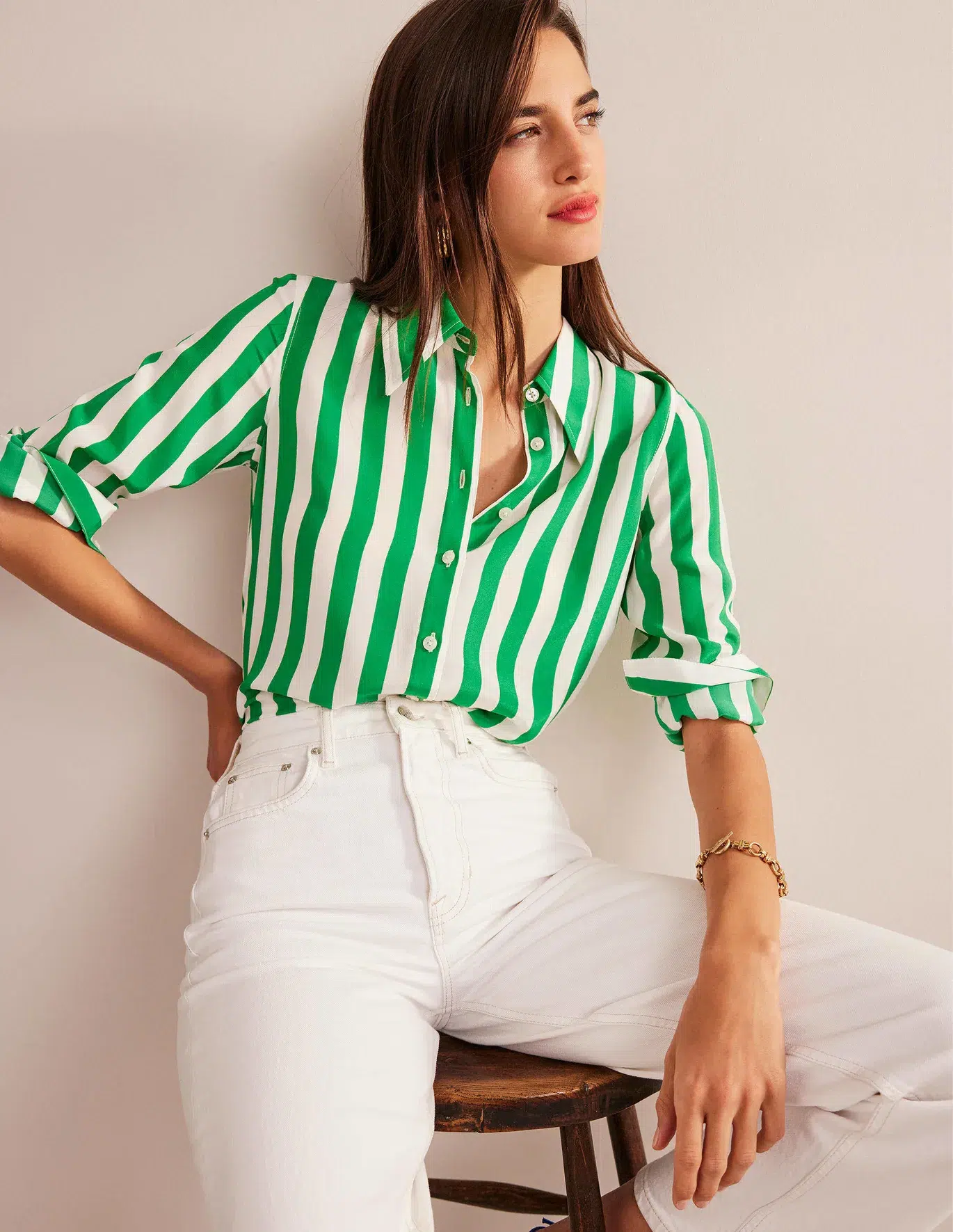 A petite model in a green and white striped silk button down and white denim pants. 