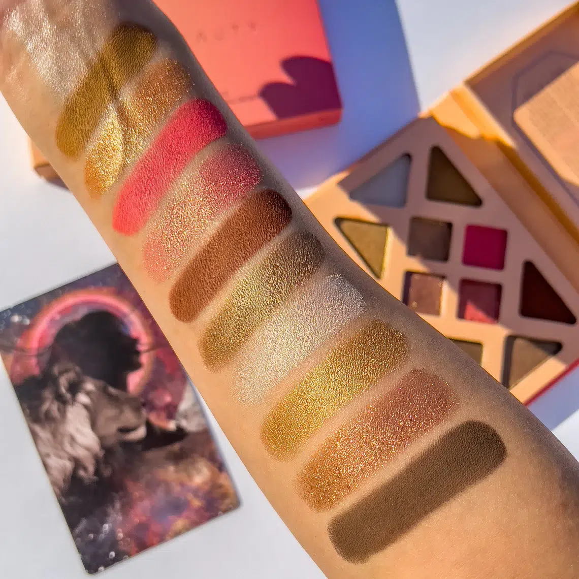 An arm shows swatches of Athr eyeshadows. 
