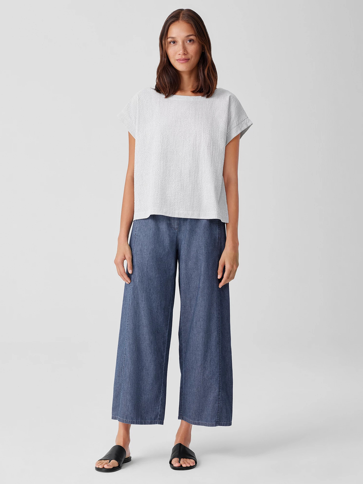 A petite model in a denim wide leg loose pants and light colored boxy top. 