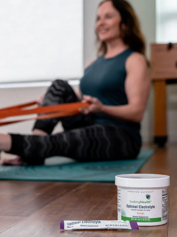 A jar and tube of the Electrolyte product in front of an out-of-focus woman exercising in the background.