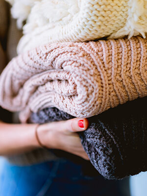 A closeup of a hand holding a stack of knitted items. 