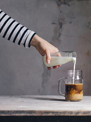 A hand pours milk into a jar of coffee. 