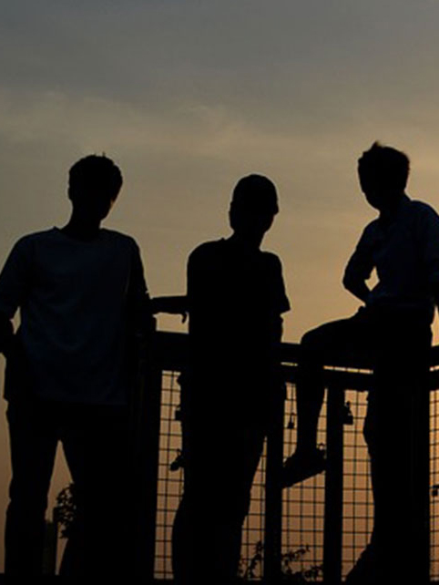 The silohuettes of three people against a sunset on a dock. 