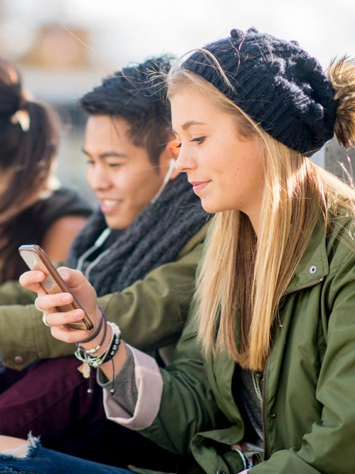 A teen girl looks at her phone. 